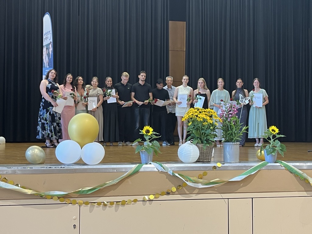 Absolvent:innen der Höheren Handelsschule mit Rosen auf der Bühne