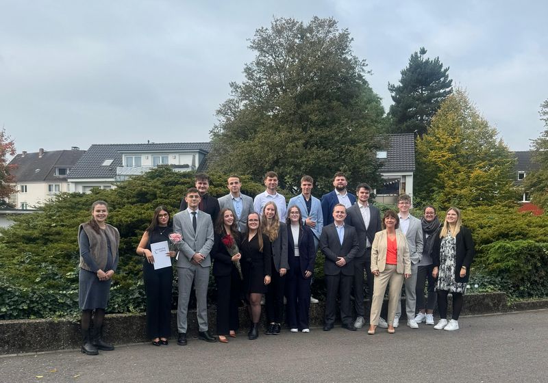 Gruppenfoto der 35 angehenden Bankkaufleute mit Lehrkräften und Ausbilder*innen vor dem Berufskolleg Siegburg