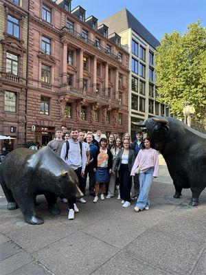 Auszubildende posieren zwischen den Bronzeskulpturen Bulle und Bär in Frankfurt am Main